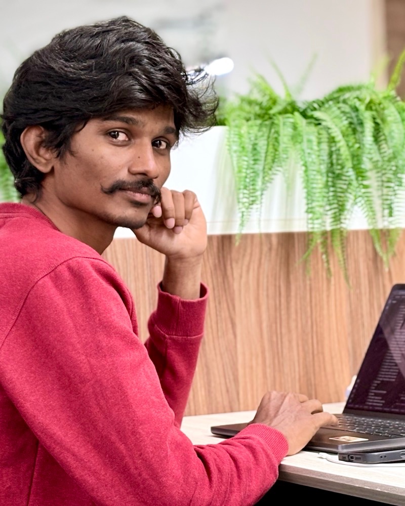 Avinash Rapolu at a desk, chin resting on one hand, laptop open